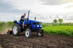 Bauer auf Traktor kultiviert das Feld. Fräsen des Bodens, Zerkleinern und Lockern des Bodens vor dem Schneiden von Reihen. landwirtschaft, landwirtschaft. vorbereitende Erdarbeiten vor dem Pflanzen einer neuen Kultur. Landbewirtschaftung foto