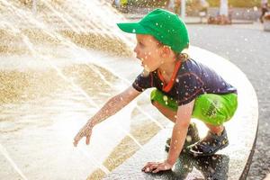 junge, der draußen mit einem brunnen spielt foto