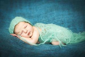 neugeborenes baby, das süß auf einem blauen teppich in der blauen kappe schläft foto