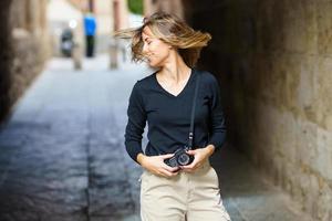 glückliche fotografin, die auf der straße lächelt und haare schüttelt foto