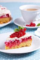 Baiser-Kuchen mit roten Johannisbeeren auf blauem Tisch foto