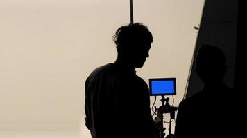 filmregisseur und fotograf sprechen oder beraten sich, um ein studioset zu erstellen, bevor sie video- und silhouettenhintergrundbeleuchtung aufnehmen. foto