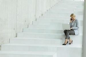 Geschäftsfrau mit Handy auf modernen Bürotreppen foto