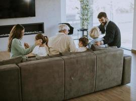 Familie mit mehreren Generationen, die zu Hause auf dem Sofa sitzt und fernsieht foto