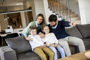 junge familie, die zusammen auf dem sofa im wohnzimmer fernsieht foto