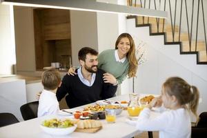 junge glückliche familie, die beim frühstücken am esstisch spricht foto