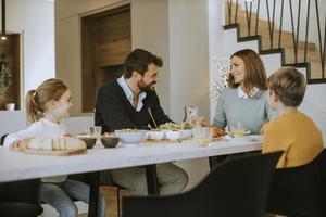 junge glückliche familie, die beim frühstücken am esstisch spricht foto