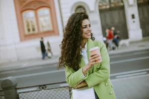 junge Frau auf der Straße mit Kaffee zum Mitnehmen foto