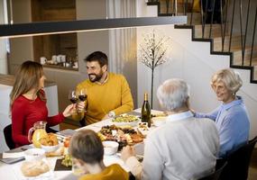 glückliche familie, die zu hause mit rotwein zu abend isst foto