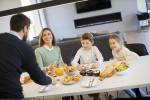 junge glückliche familie, die beim frühstücken am esstisch spricht foto