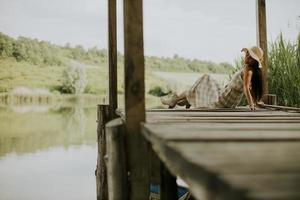 entspannende junge Frau auf Holzsteg am See foto