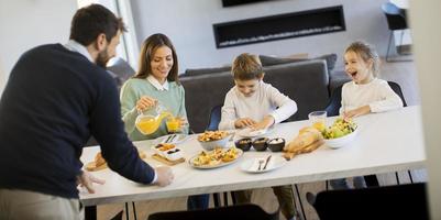 junge glückliche familie, die beim frühstücken am esstisch spricht foto