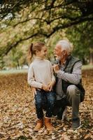 Großvater verbringt am Herbsttag Zeit mit seiner Enkelin im Park foto