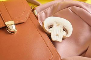 Rucksack und Tasche aus Öko-Leder und Champignons auf gelbem Grund, veganes Leder foto