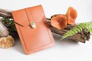 braune Tasche aus Öko-Leder, Pilzen und Farn auf grauem Hintergrund foto