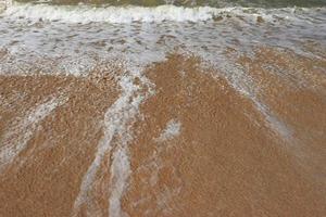 Wellen am Ufer des tropischen schönen Sandstrandes an einem sonnigen Tag foto