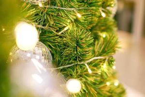 verschwommener weihnachtsball und bokeh der weihnachtsbeleuchtung mit kristallkugel und weihnachtslicht, das am weihnachtstag auf kiefernbaum dekoriert ist. foto