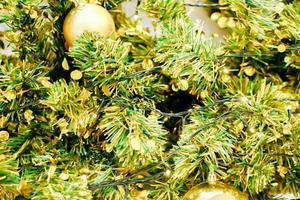 Closeup Plastikkiefernblätter und goldener Weihnachtsball mit Weihnachtsbeleuchtung im Vollbildhintergrund. foto