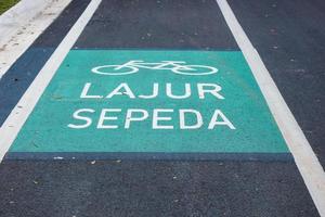 Fahrradwegschild in Gelb mit durchgezogenen Linien auf Asphaltstraße in Indonesien. foto