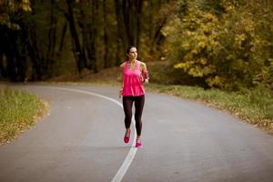 junge Fitnessfrau, die am Waldweg läuft foto