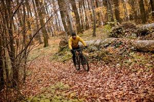 junger mann, der durch den herbstwald radelt foto