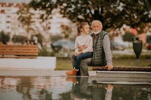 Großvater verbringt am Herbsttag Zeit mit seiner Enkelin am kleinen Wasserbecken im Park foto