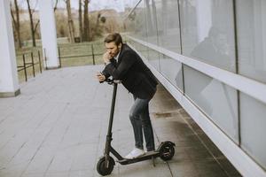 Junger Geschäftsmann mit Elektroroller foto