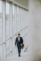 Junger Geschäftsmann mit Aktenkoffer, der die Treppe hinaufgeht foto