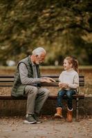 großvater, der am herbsttag mit seiner enkelin im park rote hände schlägt foto