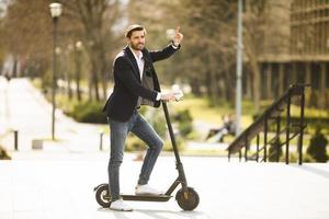 junger Geschäftsmann mit Handy auf Elektroroller foto