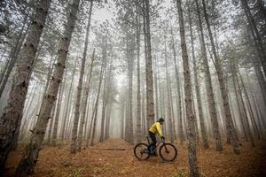 junger mann, der durch den herbstwald radelt foto