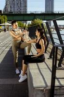 junge frauen in sportkleidung, die sich nach dem training an einer flusspromenade ausruhen foto