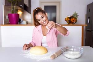 junge frau knetet teig in der küche, hausgemachte bäckerei. Frau, die Teig auf Küchentisch knetet foto