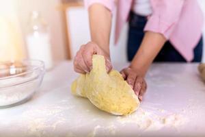 Nahaufnahme von weiblichen Bäckerhänden, die Teig kneten und Brot backen. Koch- und Heimkonzept - Nahaufnahme von weiblichen Händen, die zu Hause Teig kneten foto