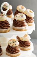 Cupcakes mit Schokoladenglasur und kleinen Donuts foto