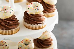 Cupcakes mit Schokoladenglasur und kleinen Donuts foto