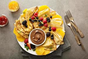 dünne Crêpes mit frischen Früchten und Beeren foto