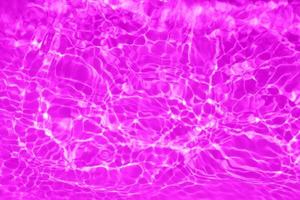 defocus verschwommene, transparente, violette, klare, ruhige wasseroberflächenstruktur mit spritzern und blasen. trendiger abstrakter naturhintergrund. wasserwellen im sonnenlicht mit kopierraum. rosa Wassertropfen glänzen foto