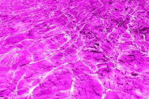 defocus verschwommene, transparente, violette, klare, ruhige wasseroberflächenstruktur mit spritzern und blasen. trendiger abstrakter naturhintergrund. wasserwellen im sonnenlicht mit kopierraum. rosa Wassertropfen glänzen foto