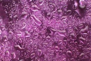 Wassertropfen auf violettem Hintergrund. abstrakter lila Hintergrund. Wassertropfen auf Glas. foto