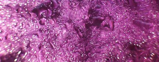 Wassertropfen auf violettem Hintergrund. abstrakter lila hintergrund. Wassertropfen auf Glas. Banner foto