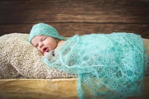 neugeborenes baby, das auf einem hölzernen hintergrund im trog schläft foto