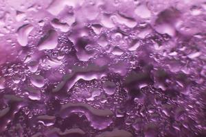 Wassertropfen auf violettem Hintergrund. abstrakter lila Hintergrund. Wassertropfen auf Glas. foto