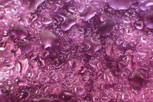 Wassertropfen auf violettem Hintergrund. abstrakter lila Hintergrund. Wassertropfen auf Glas. foto