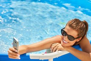 Nahaufnahme einer attraktiven Frau, die sich am Swimmingpool im Hinterhof entspannt foto