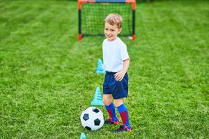 kleiner Junge, der draußen Fußball übt foto