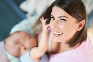 glückliche Mutter, die neugeborenes Baby stillt foto