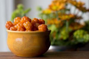 cloudberry.rubus chamaemorus.close up wilde Beere in orangefarbener Schale auf Holztisch, Herbsternte in den norwegischen Bergen bei Hemsedal, Buskerud, Norwegen, Foto zum Drucken auf Kalender, Poster, Tapete