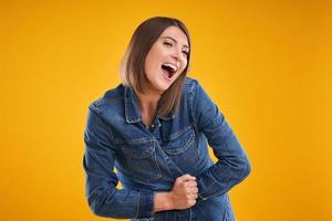 Nahaufnahme einer Frau in Jeansjacke, die auf gelbem Hintergrund in die Kamera blickt foto