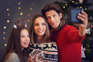 schöne familie, die weihnachten zu hause feiert und sofortbilder macht foto